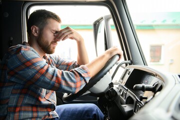 truck driver at wheel pinching bridge of nose